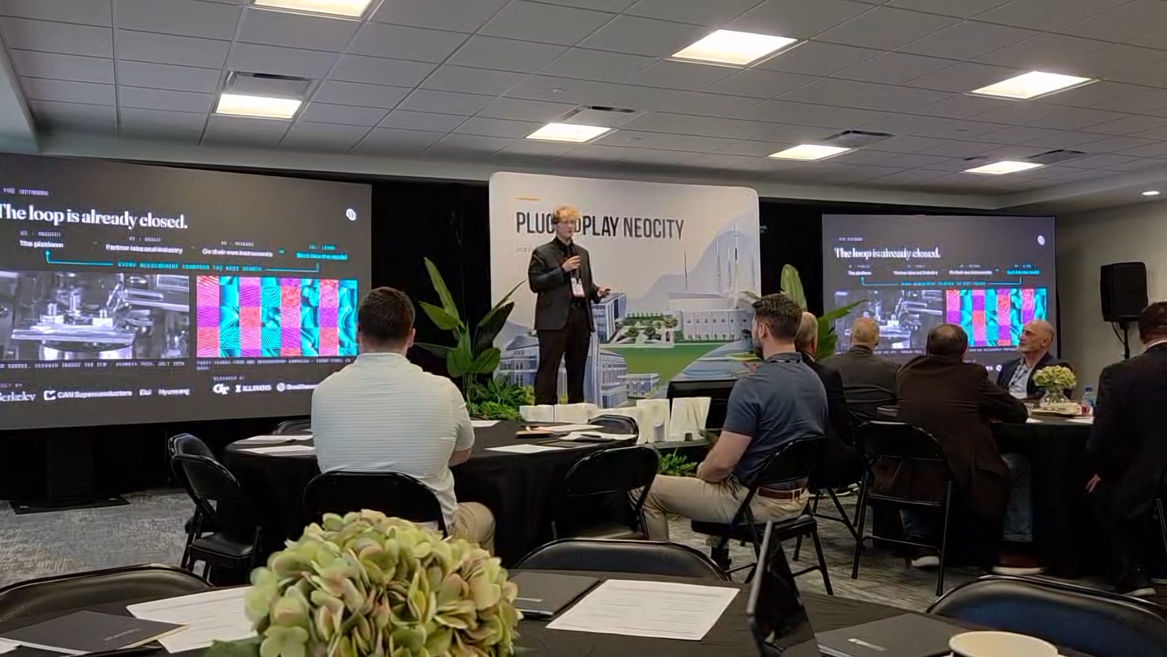 Davis Rens on stage at Plug and Play NeoCity, presenting the platform to a seated audience